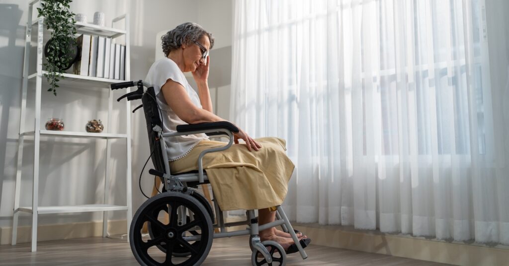 Sad elderly woman sitting alone in wheelchair at a nursing home | Burg Simpson